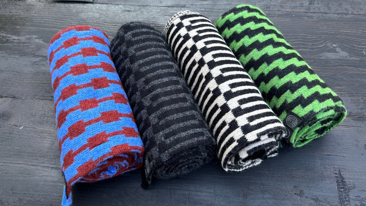 Rolled merino lambswool knit scarves in pulse, link, rickrack, and stripe patterns in blue-red, black-grey, black-white and green-black.