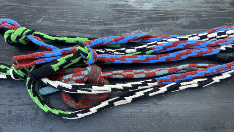 Bundle of knit neck ties with Pulse rickrack zigzag pattern in green, blue, red, black and white, tied in loose knots