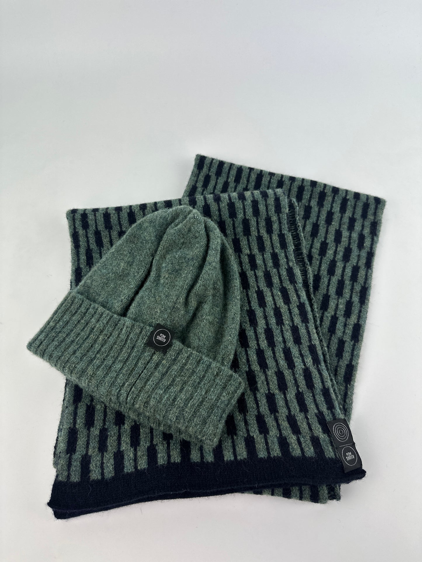 peacock green merino lambswool beanie with a double ribbed brim and a peacock green and navy blue scarf on a plain background.