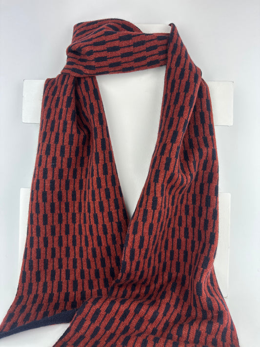 sienna brown and navy blue merino lambswool geometric patterned scarf on rack on a plain background.
