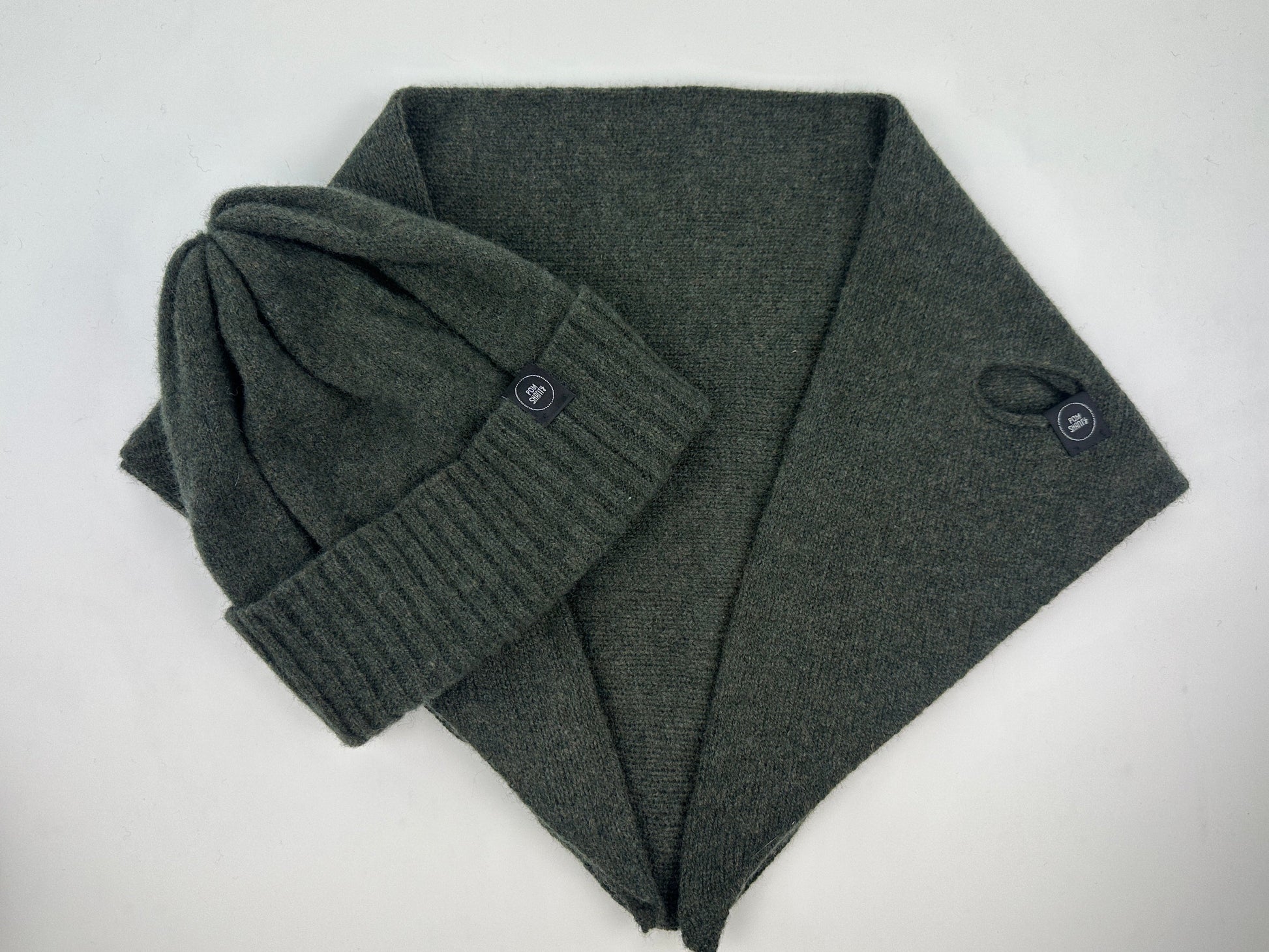 olive green coloured merino lambswool handcrafted knitted beanie with a double ribbed brim and a kerchief lying flat on a white background