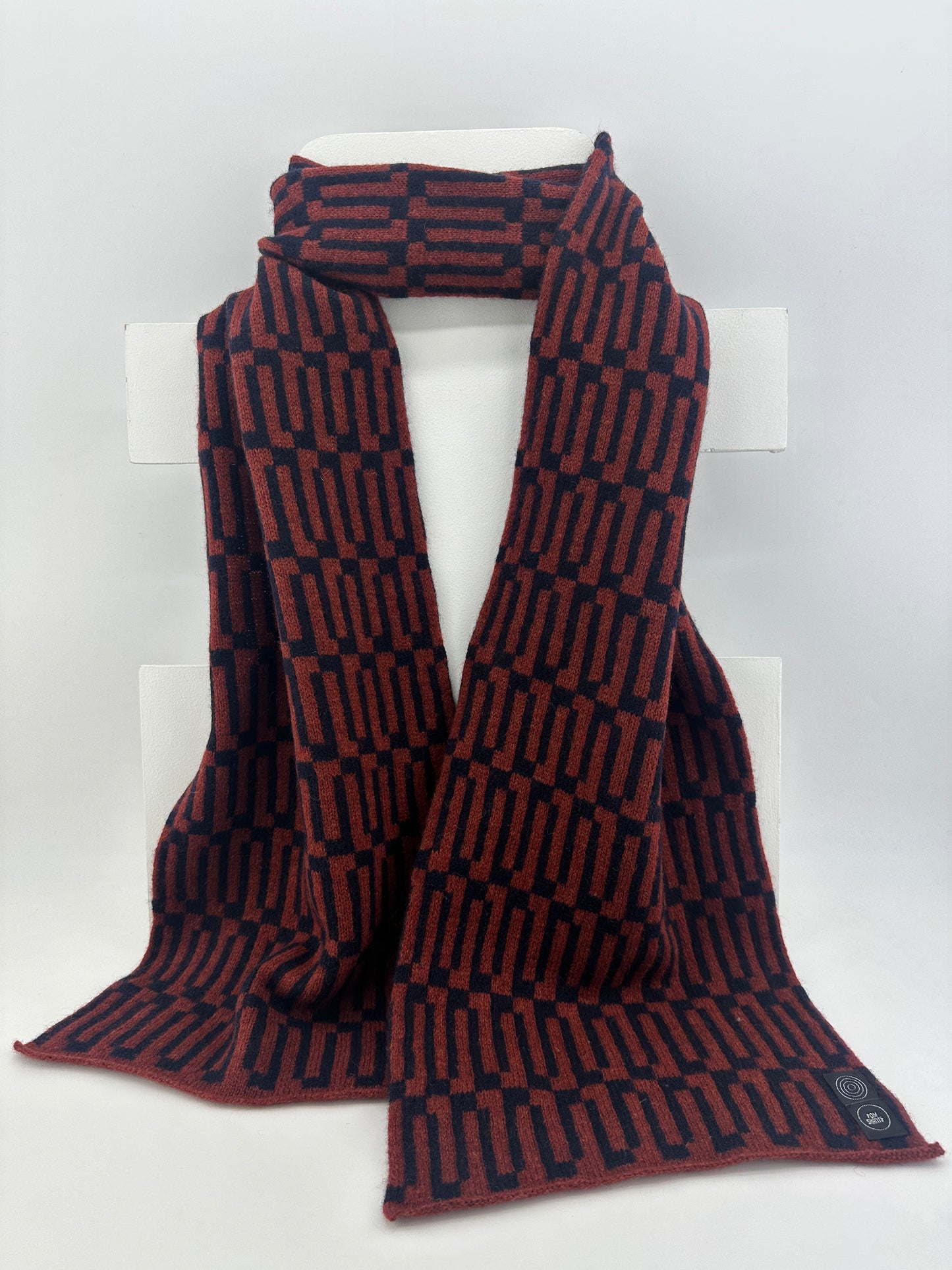 Sienna Brown and Navy Blue Merino Lambswool handcrafted Link Scarf on a white dispaly rack on a neutral background.