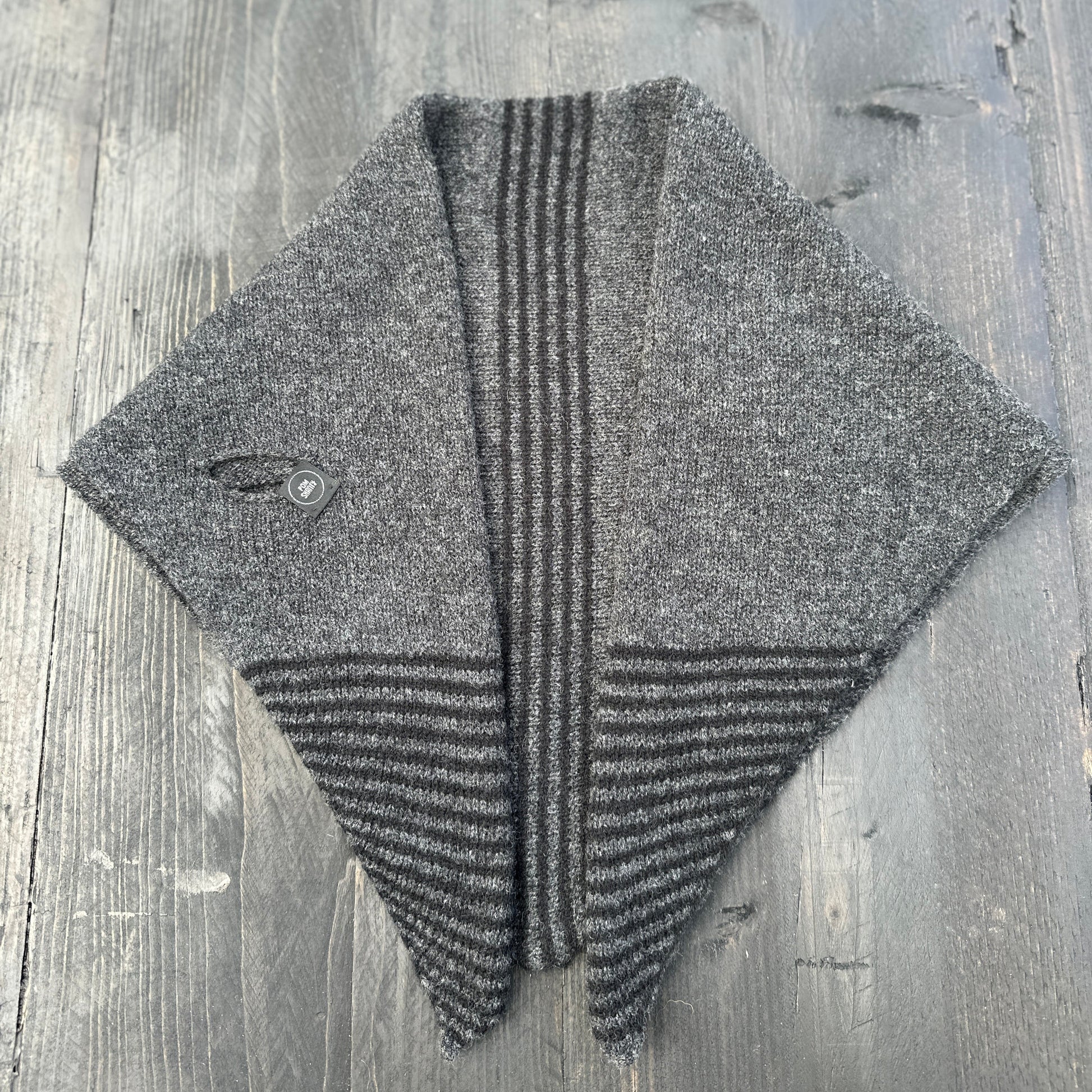 Merino lambswool double layer striped, multicoloured, charcoal grey and black pull through triangle scarf / kerchief / neckerchief for women, men, unisex on a wooden table.