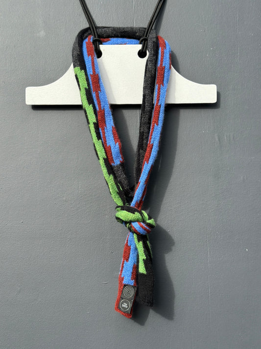 Multi-coloured pulse patterned Pom Shanty Knitwear merino lambswool neck tie hanging on a white hanger againts a grey background for men, women and unisex.