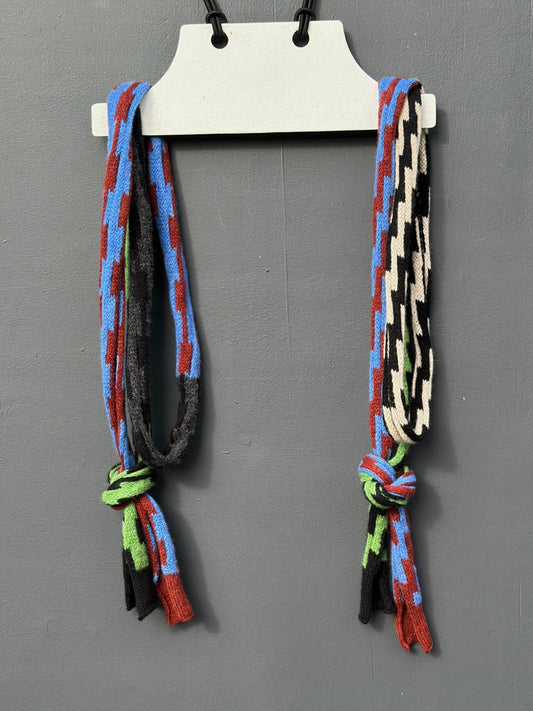 A multi-coloured pulse patterned and rick rack patterned Pom Shanty Knitwear merino lambswool neck tie hanging on a white hanger againts a grey background for men, women and unisex.