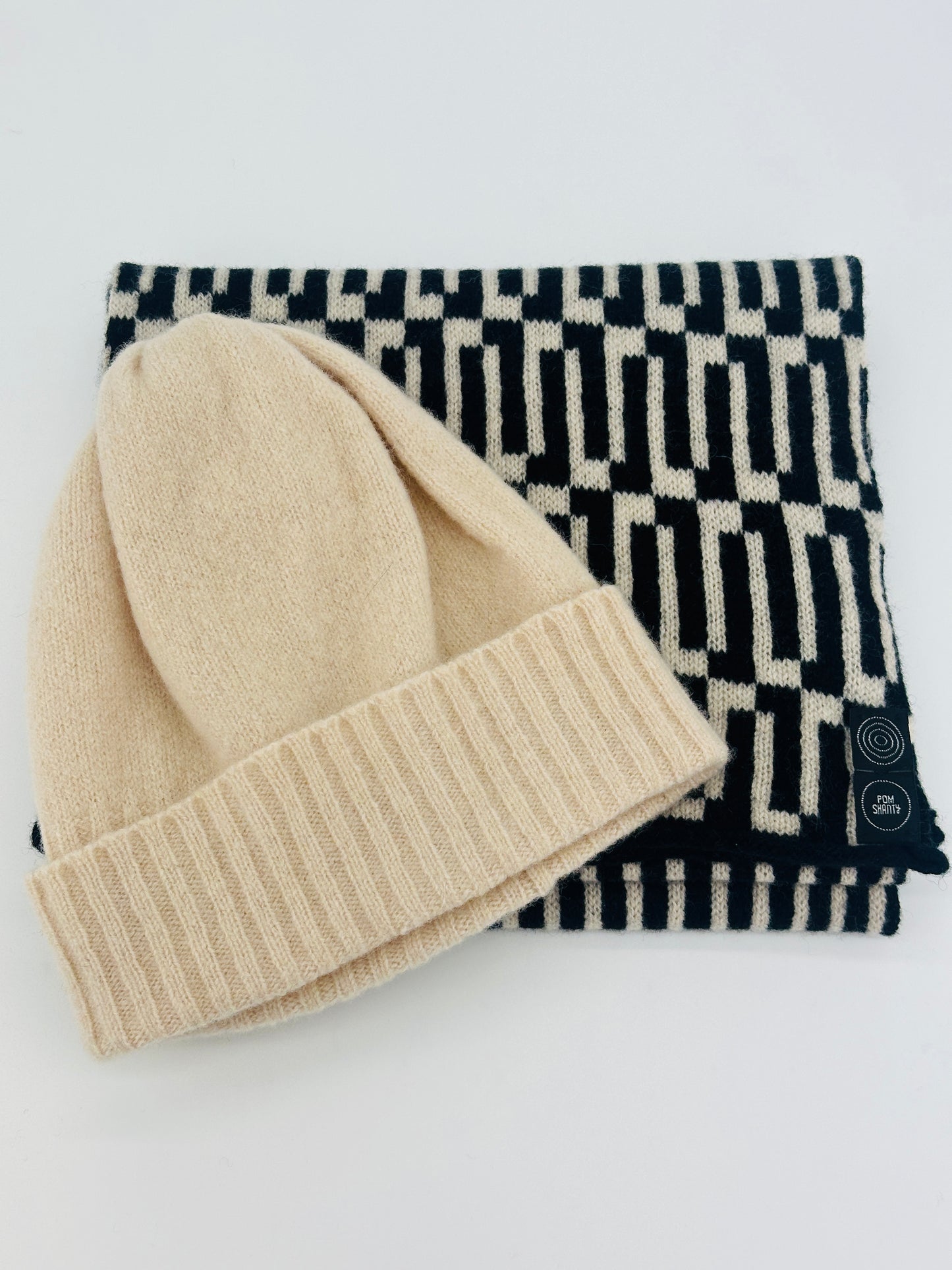 Black and oatmeal Merino Lambswool handcrafted Link Scarf wiht an oatmeal merino lambswool beaning on top, with both on a white background Pom Shanty Knitwear