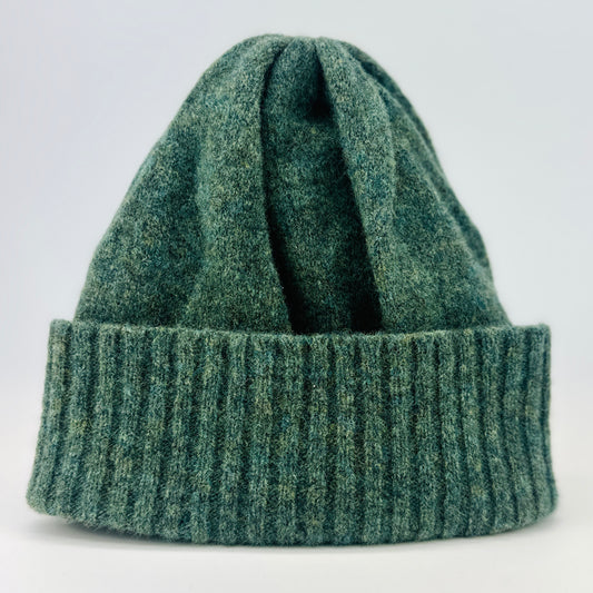 peacock green merino lambswool beanie with a double ribbed brim on a plain background.