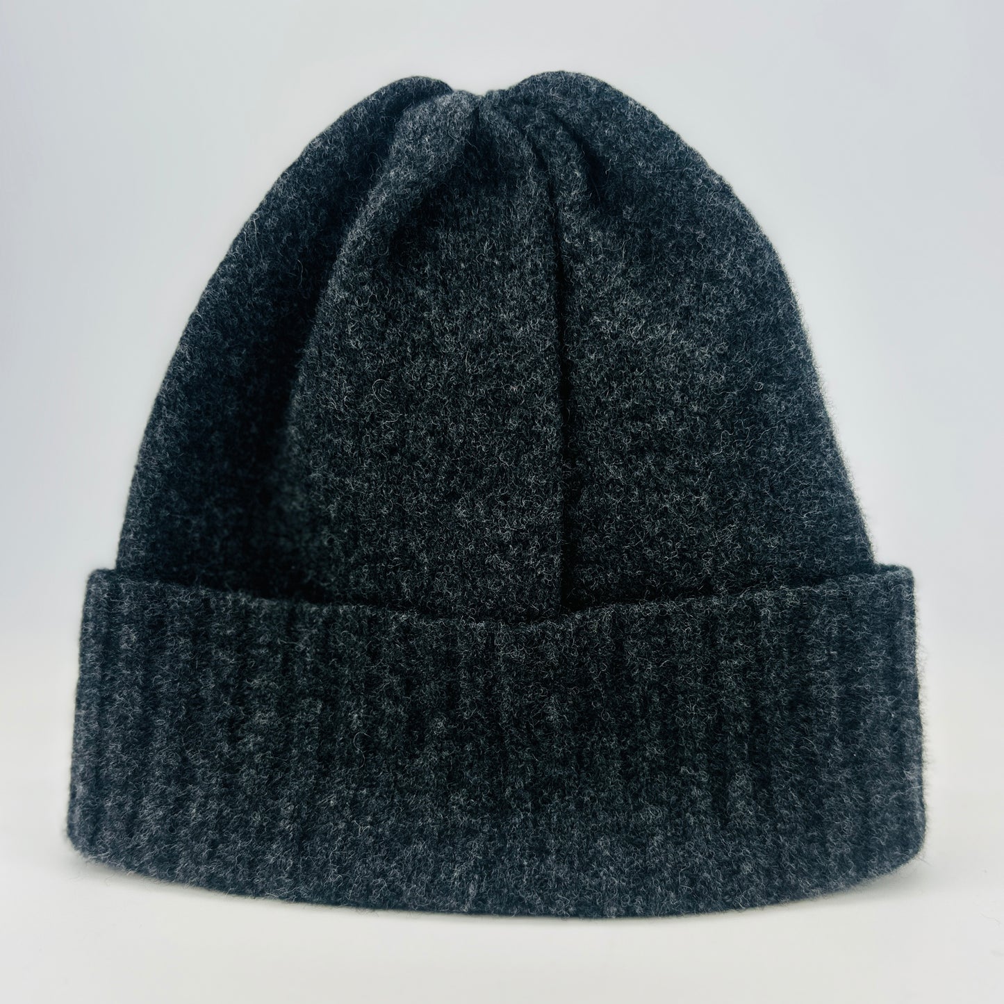 Charcoal grey coloured merino lambswool handcrafted knitted beanie with a double ribbed brim on a white background