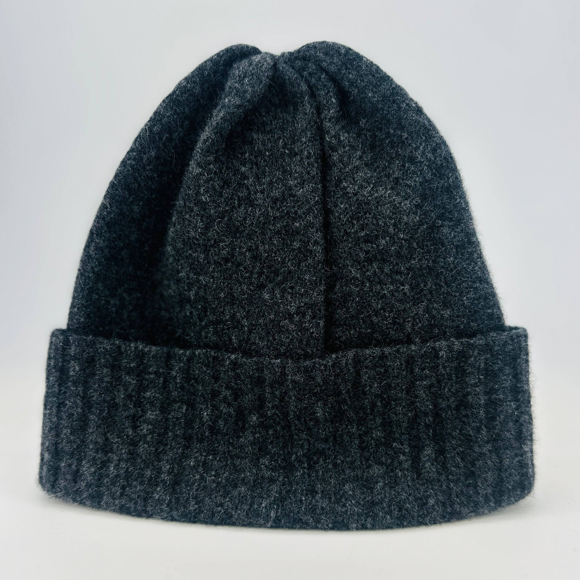 Charcoal grey coloured merino lambswool handcrafted knitted beanie with a double ribbed brim on a white background