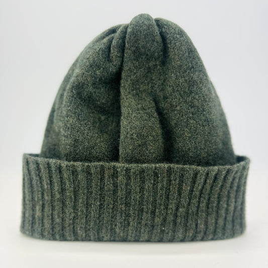 olive green merino lambswool handcrafted knitted beanie with a double ribbed brim lying flat on a background