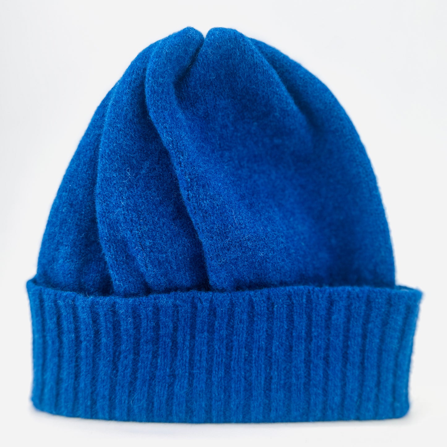 dark blue coloured merino lambswool handcrafted knitted beanie with a double ribbed brim on a neutral background