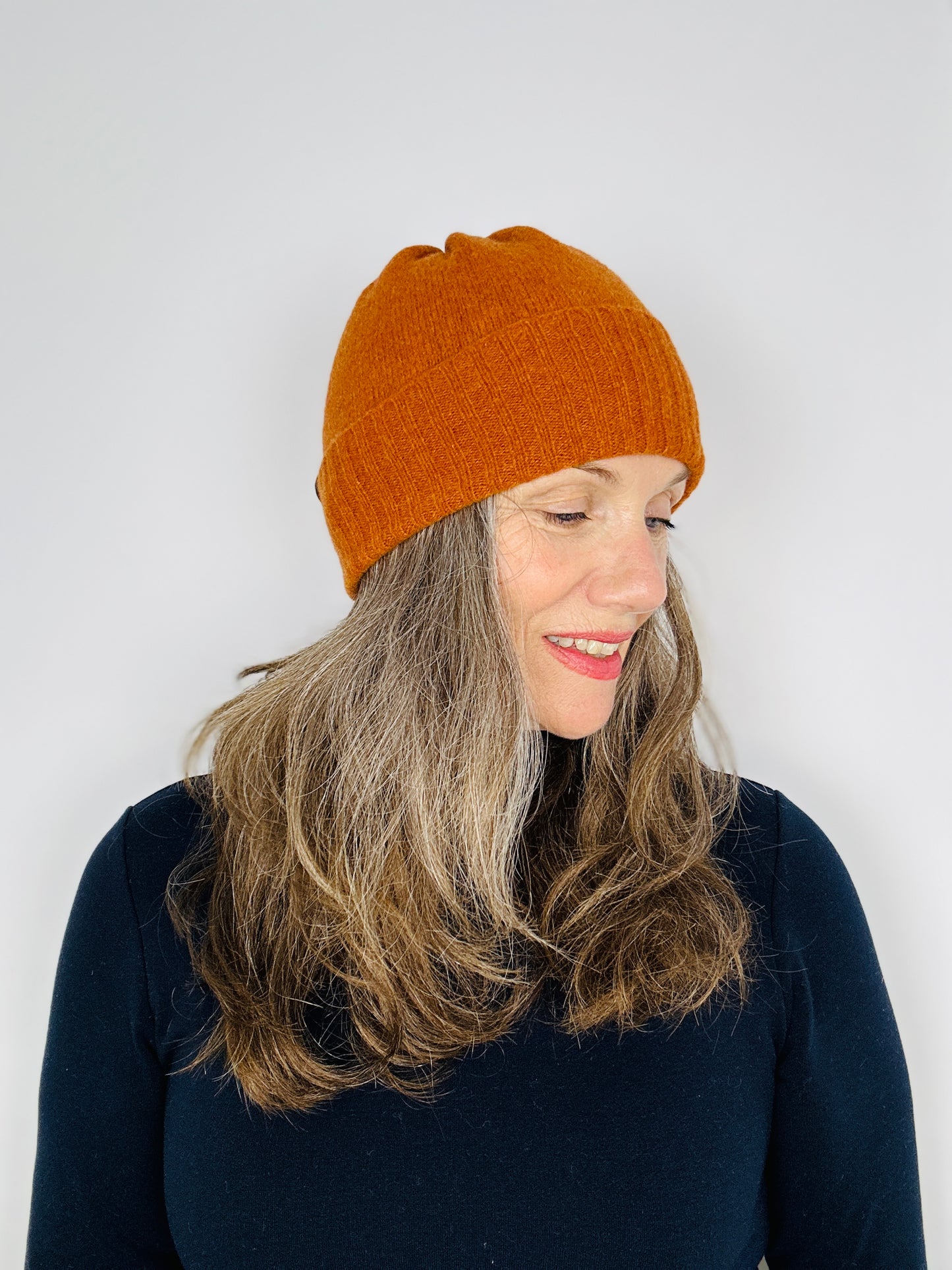 Beautiful sexy women in a black top wearing a rust coloured merino lambswool handcrafted knitted beanie