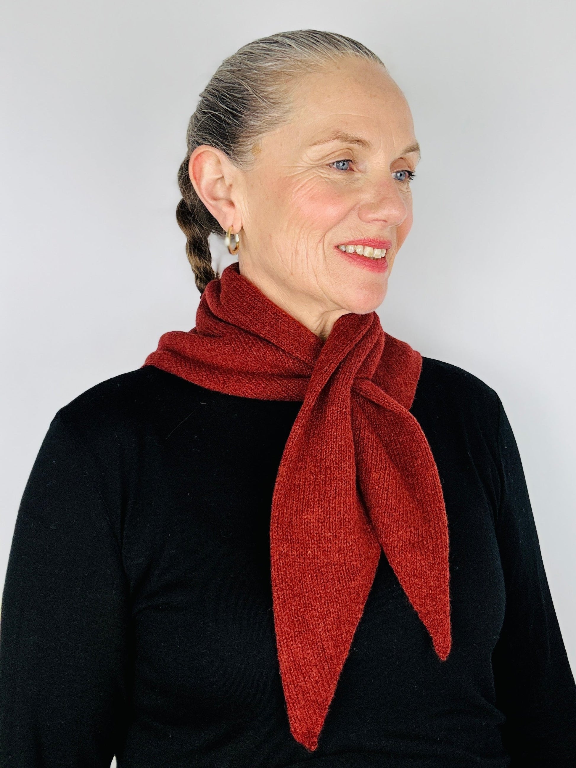 Beautiful sexy woman in a black top with her hair tied back and red lipstick on wearing merino lambswool double layer solid colour, sienna brown pull through triangle scarf / kerchief / neckerchief for women, men, unisex on a neutral background