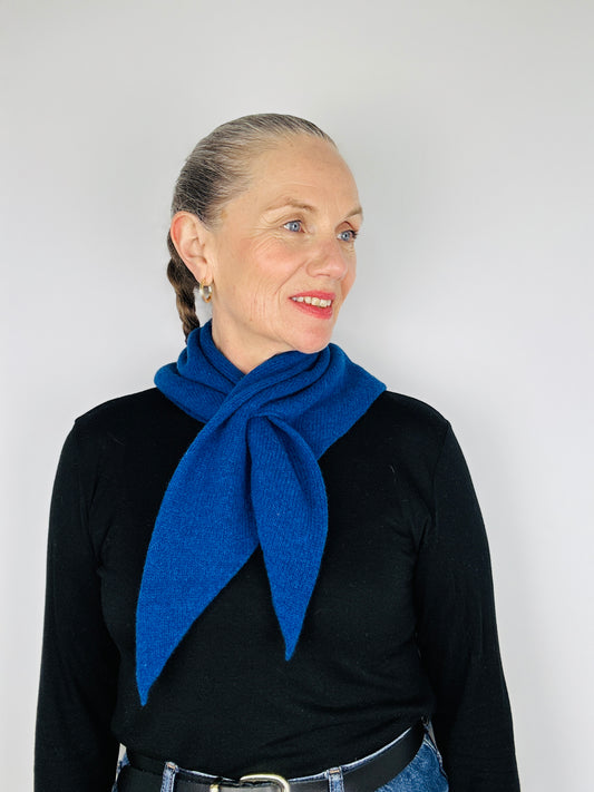 Beautiful sexy woman in a black top with her hair tied back and lipstick on wearing merino lambswool double layer solid colour, dark blue pull through triangle scarf / kerchief / neckerchief for women, men, unisex on a neutral background
