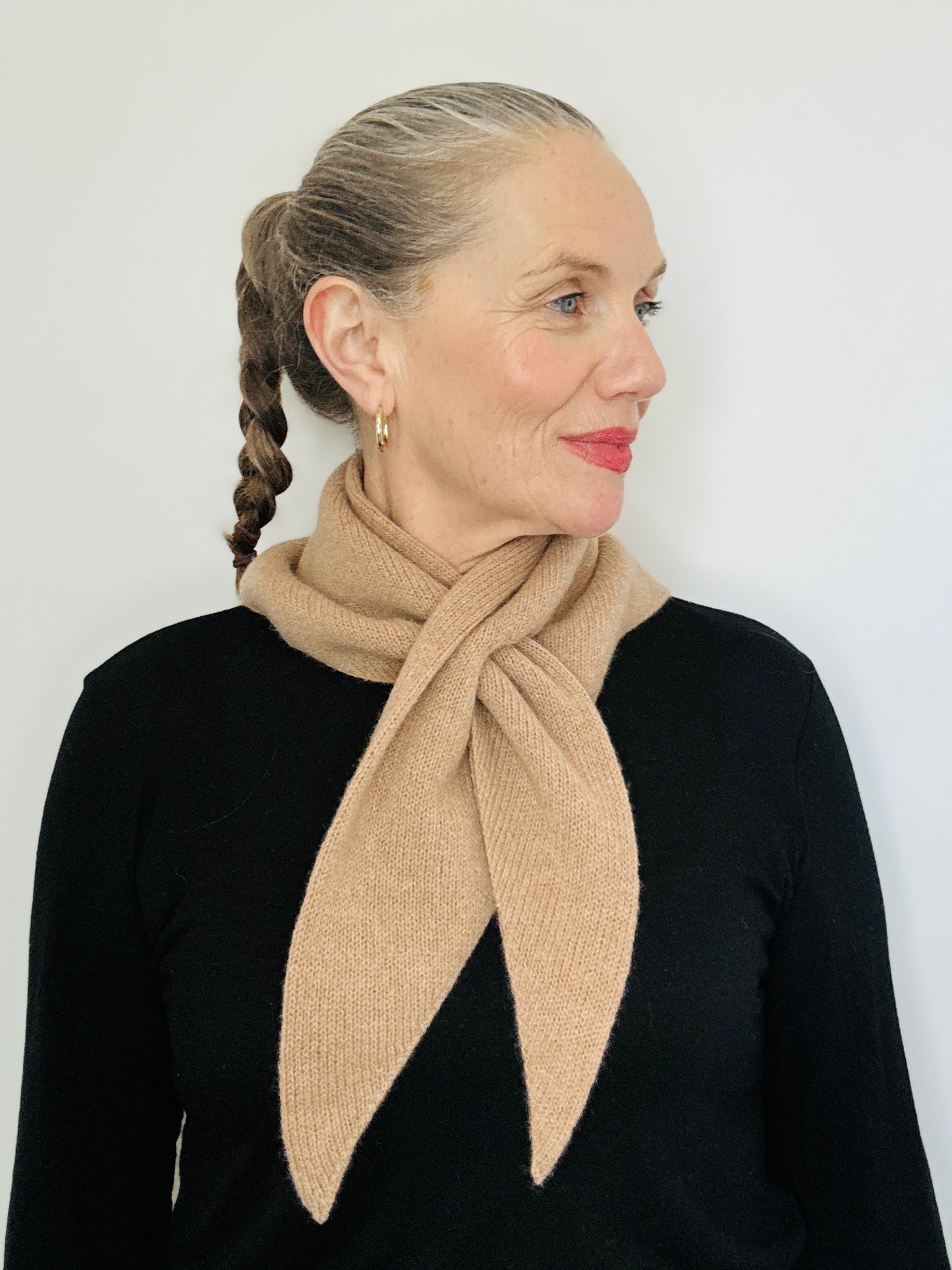 Beautiful sexy woman in a black top with her hari tied back and red lipstick on wearing merino lambswool double layer solid colour, camel brown pull through triangle scarf / kerchief / neckerchief for women, men, unisex