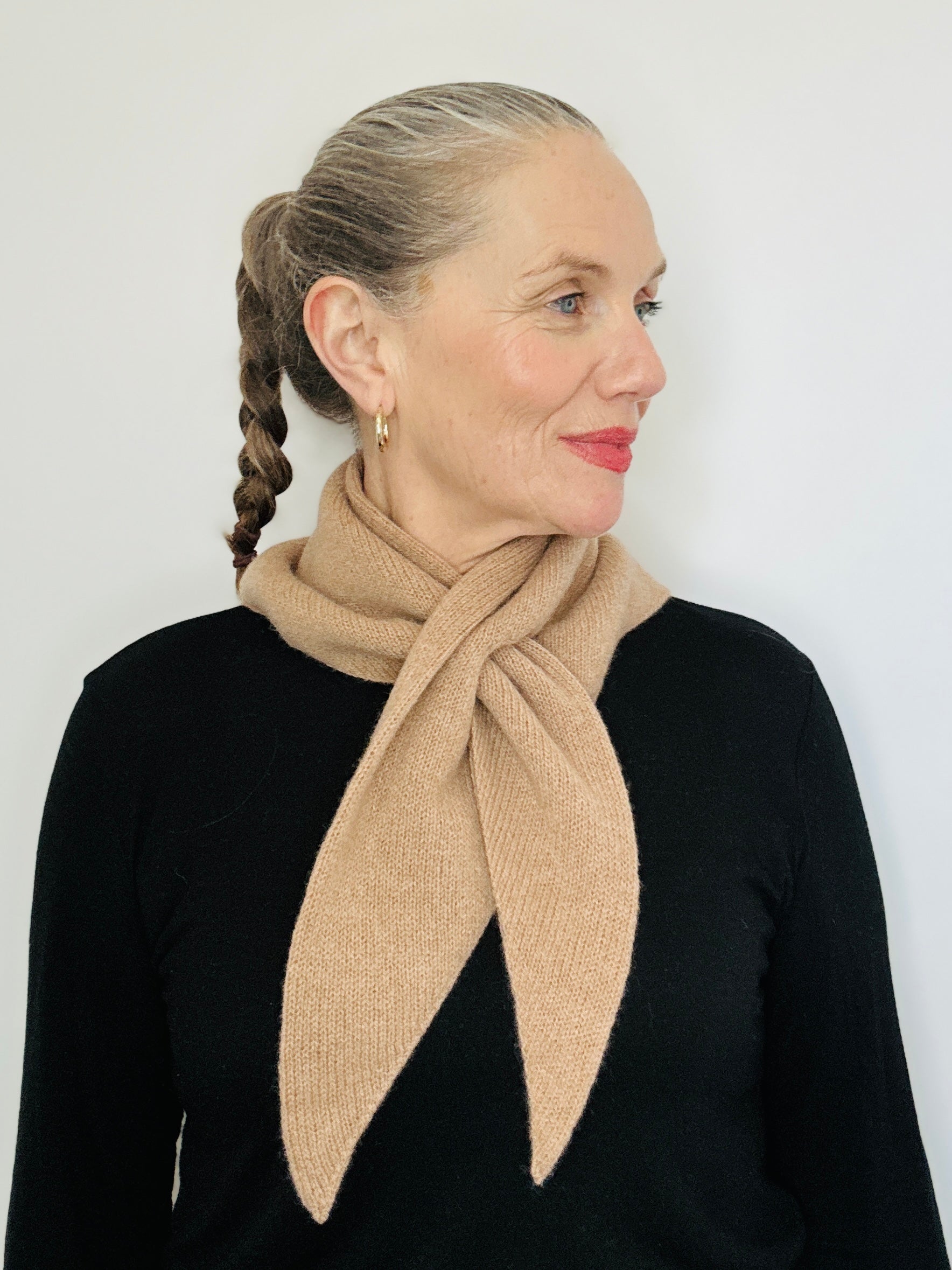 Beautiful sexy woman in a black top with her hari tied back and red lipstick on wearing merino lambswool double layer solid colour, camel brown pull through triangle scarf / kerchief / neckerchief for women, men, unisex