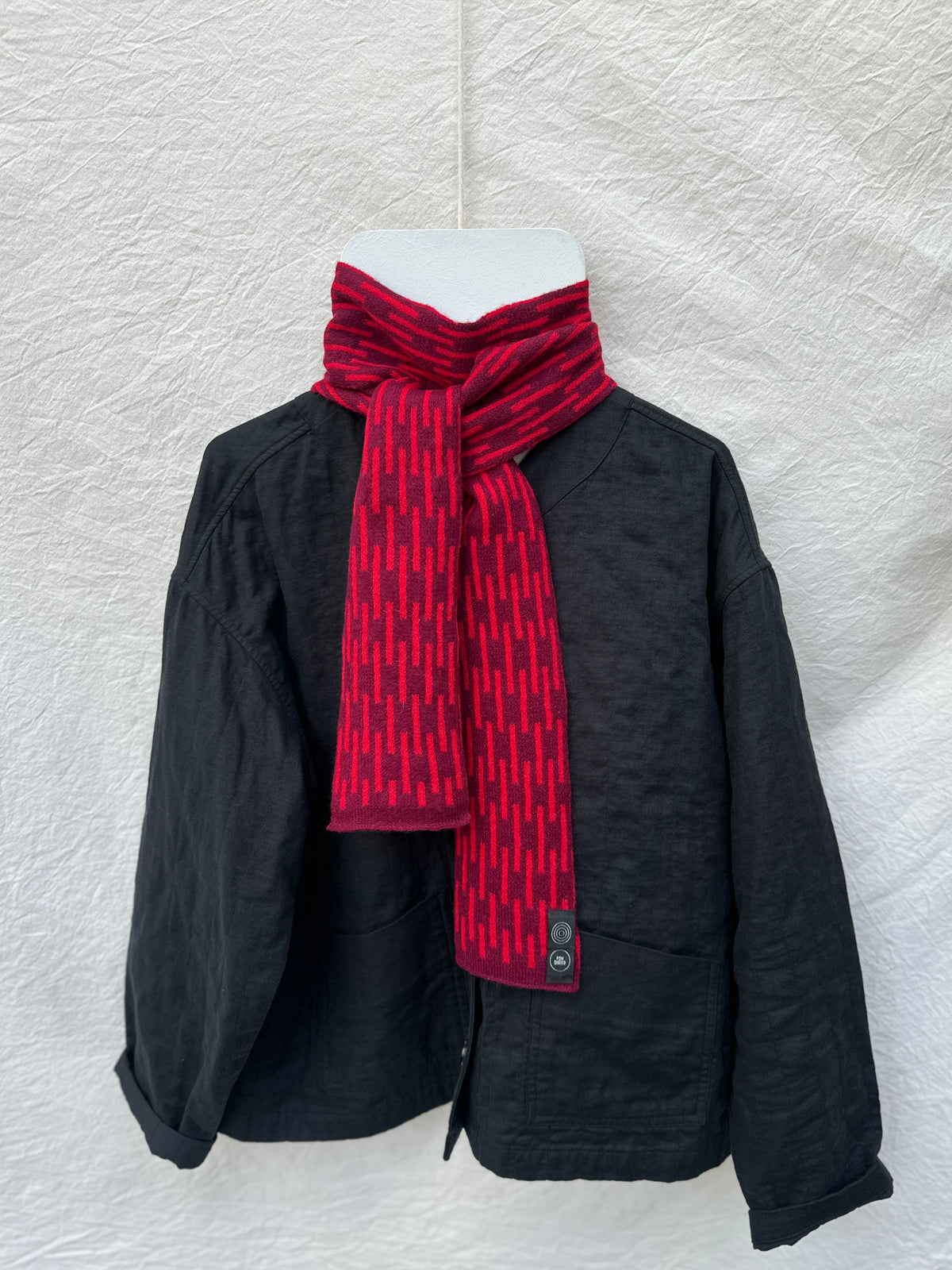 Burgundy and Red Rain Skinny Scarf, lambswool, draped over a black jacket