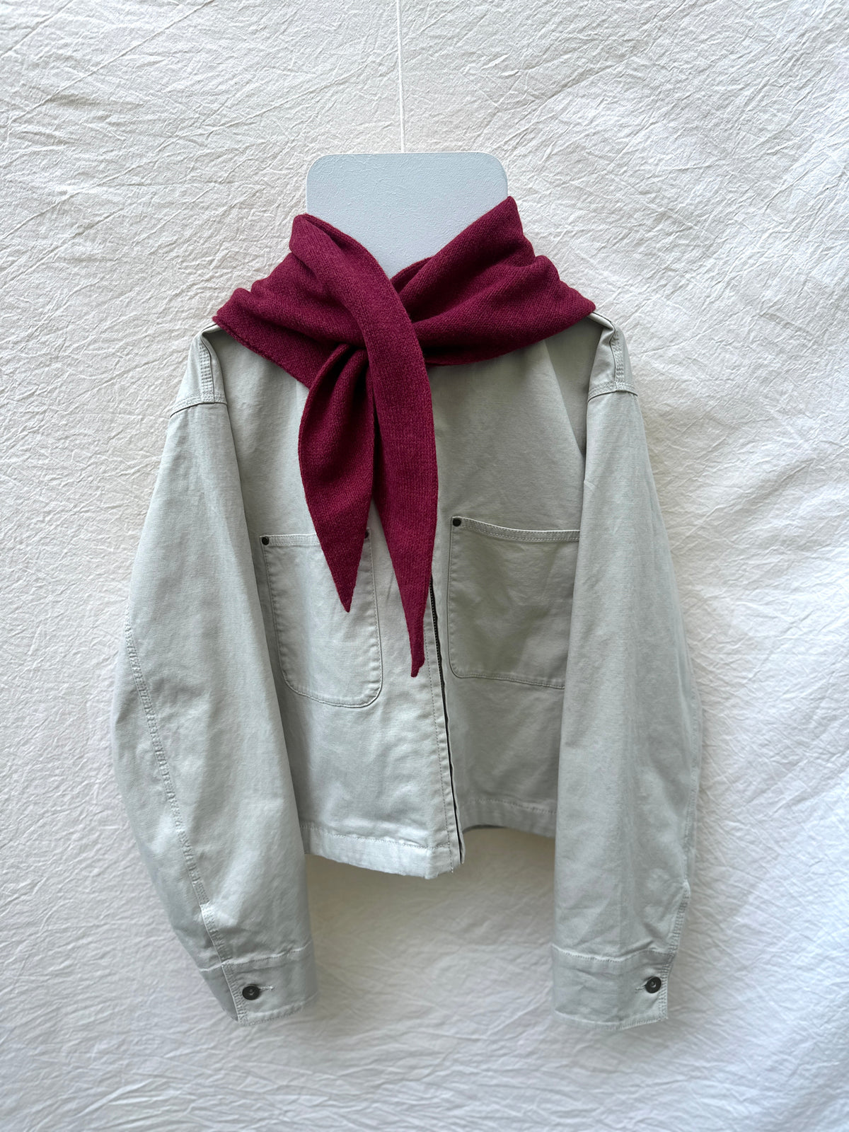 Cherry Red Triangle Scarf, merino wool, draped over a cream jacket