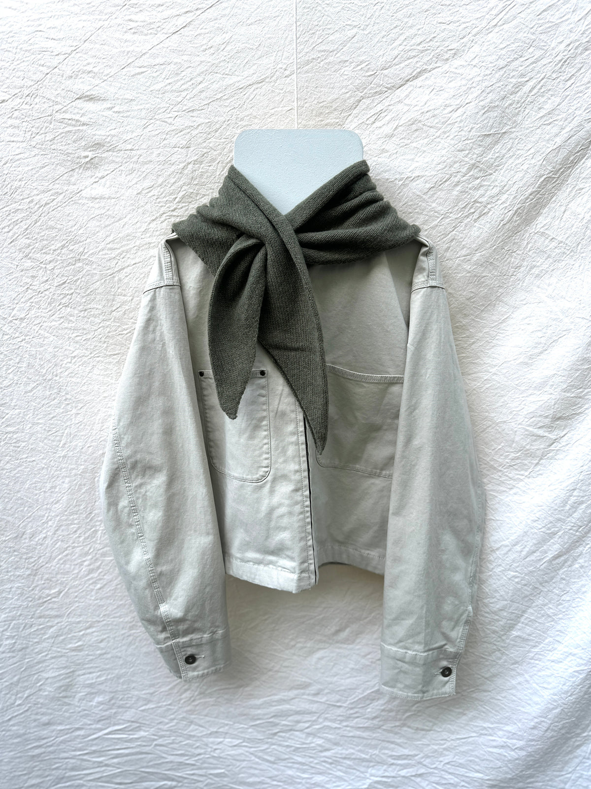 Olive Triangle Scarf, merino wool, draped over a cream jacket